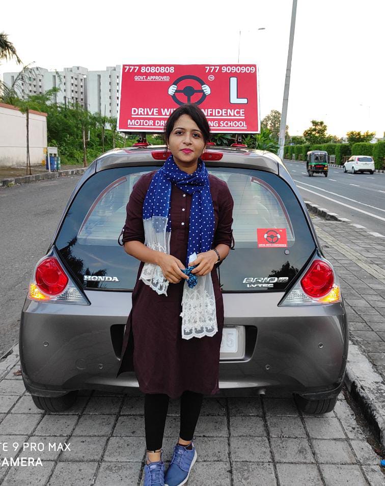 A confident DWC student standing with the DWC training car in Surat